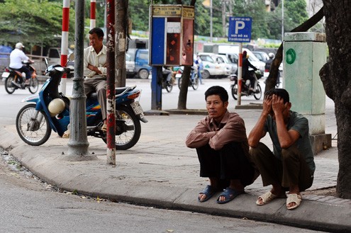 Những người chờ việc làm ngồi thu mình dưới gốc cây.